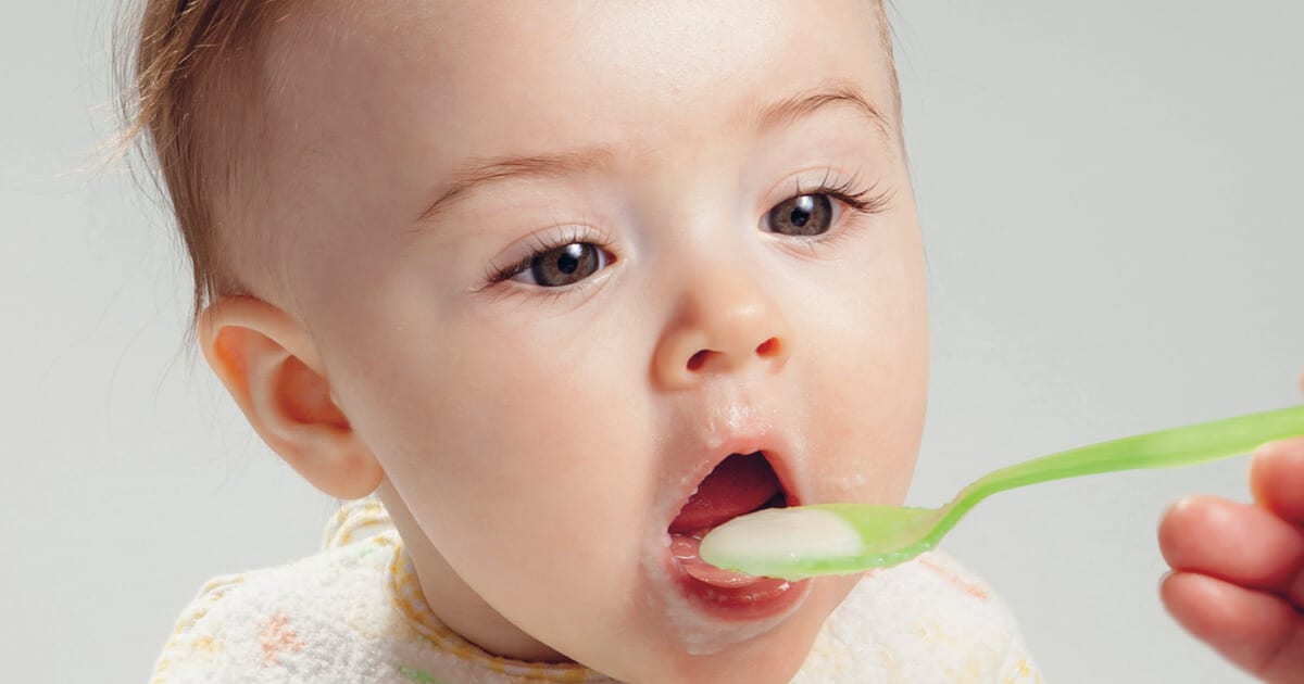 Baby eating solids off a spoon